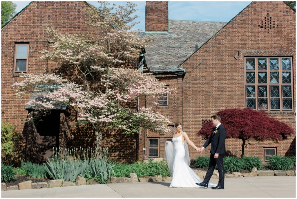 A bride and groom walking in front of the Tudor house at mason's cove wedding venue